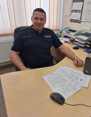 Zdjęcie przedstawiające policjanta przy biurku.