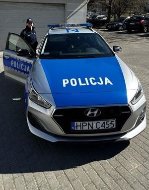 Zdjęcie przedstawiające policjantkę przy radiowozie.