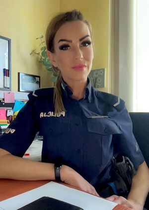 Zdjęcie przedstawiające policjantkę, siedzącą przy biurku.