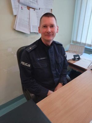 Zdjęcie przedstawiające policjanta siedzącego przy biurku.