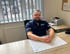 Zdjęcie przedstawiające policjanta przy biurku.
