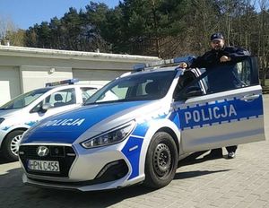 Zdjęcie przedstawiające policjanta przy radiowozie.