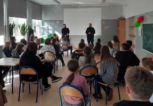 Zdjęcie przedstawiające dwóch policjantów, prowadzących zajęcia profilaktyczne z uczniami.