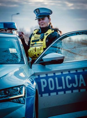 Zdjęcie przedstawiające policjantkę ruchu drogowego stojącą przy radiowozie.