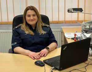 Zdjęcie przedstawiające policjantkę siedzącą przy biurku.