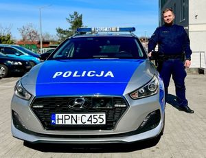 Zdjęcie przedstawiające policjanta przy radiowozie.