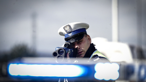Zdjęcie przedstawiające policjanta podczas wykonywania pomiaru prędkości.