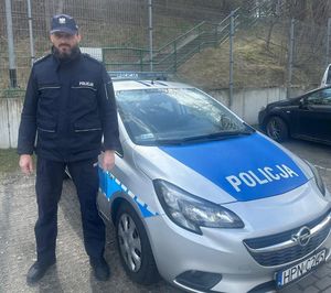 Zdjęcie przedstawiające policjanta stojącego przy radiowozie.