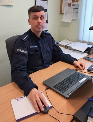Zdjęcie przedstawiające policjanta siedzącego przy biurku.