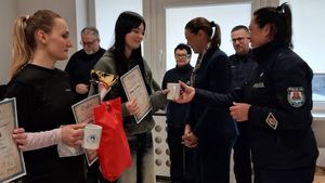 Zdjęcie przedstawiające policjantkę wręczającą nagrodę uczestniczce zawodów. Na zdjęciu są również inny zawodnicy i policjant.