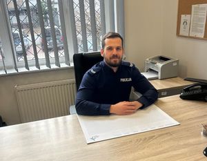 Zdjęcie przedstawiające policjanta siedzącego przy biurku.