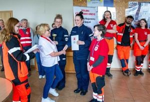 Zdjęcie przedstawiające policjantki podczas wręczania dyplomów po zakończonych zawodach młodzieżowych z pierwszej pomocy medycznej.