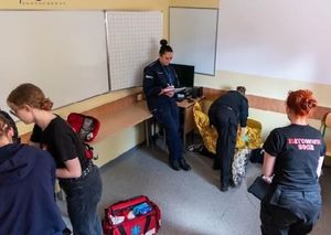 Zdjęcie przedstawiające policjantkę podczas sędziowania w zawodach młodzieżowych z pierwszej pomocy medycznej.