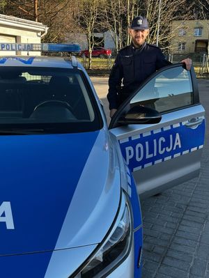 Zdjęcie przedstawiające policjanta przy radiowozie.