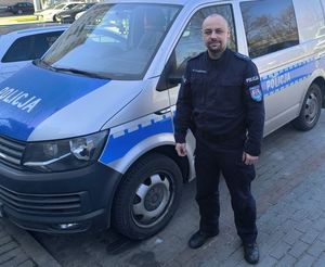 Zdjęcie przedstawiające policjanta stojącego przy radiowozie.