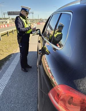 Zdjęcie przedstawiające policjanta podczas kontroli kierowcy pojazdu osobowego.