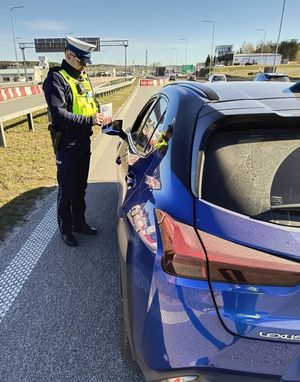 Zdjęcie przedstawiające policjanta podczas kontroli kierowcy pojazdu osobowego.
