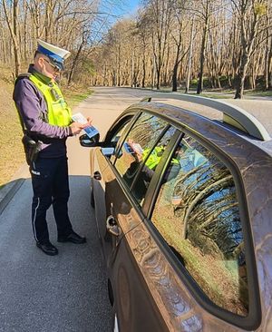 Zdjęcie przedstawiające policjanta podczas kontroli kierowcy pojazdu osobowego.