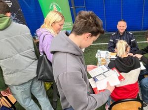 Zdjęcie przedstawiające policjanta podczas Targów Pracy. Policjant rozmawia z uczestnikami targów.