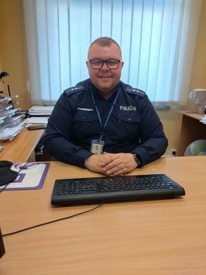 Zdjęcie przedstawiające policjanta, który siedzi przy biurku.