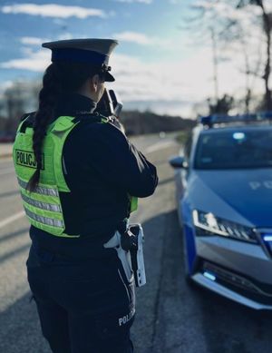 Zdjęcie przedstawiające policjantkę podczas wykonywania pomiaru prędkości.