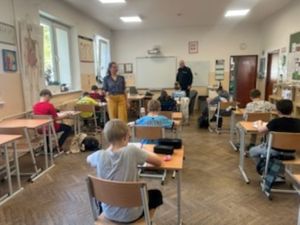 Zdjęcie przedstawiające policjanta, nauczycielkę i dzieci.