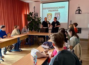 Zdjęcie przedstawiające policjantkę i strażnika miejskiego podczas spotkania z licealistami.