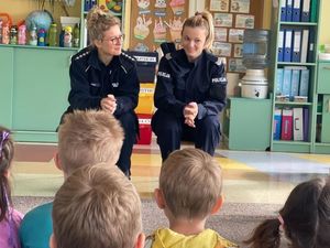 Zdjęcie przedstawiające policjantki podczas prowadzenia zajęć z przedszkolakami. Na zdjęciu widać też dzieci siedzące tyłem do fotografii.