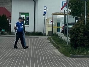 Zdjęcie przedstawiające policjanta, prowadzącego zatrzymanego mężczyznę.