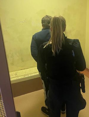 Zdjęcie przedstawiające policjantkę, która wprowadziła zatrzymanego mężczyznę do policyjnej celi.
