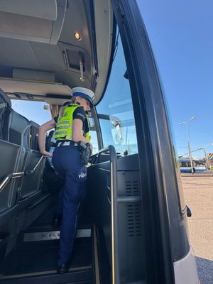 Zdjęcie przedstawiające policjantkę wchodzącą do autokaru.