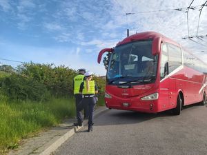 Zdjęcie przedstawiające policjantkę i policjanta idących do autokaru.