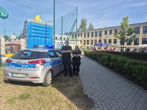 Zdjęcie przedstawiające dzielnicową i dzielnicowego przy radiowozie stojących przed przedszkolem.