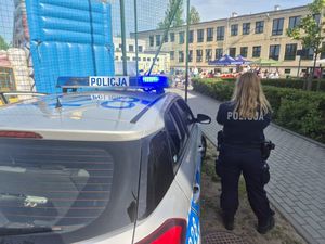 Zdjęcie przedstawiające dzielnicową przy radiowozie, stojącą przed przedszkolem.