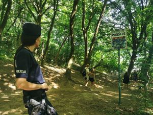 Zdjęcie przedstawiające policjantkę obserwującą turystów, którzy idą na plażę na Oksywiu.
