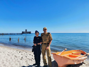Zdjęcie przedstawiające policjantkę i funkcjonariusza Państwowej Straży Pożarnej podczas służby na plaży na Oksywiu.