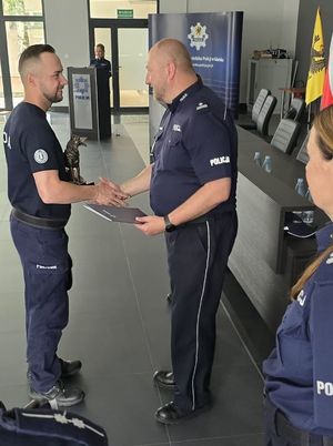 Zdjęcie przedstawiające  przewodnika psa służbowego podczas przyjmowania dyplomu.