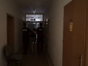 Zdjęcie przedstawiające policjantów prowadzących zatrzymanego mężczyznę.