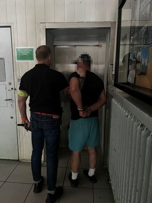 Zdjęcie przedstawiające policjanta prowadzącego zatrzymanego mężczyznę.
