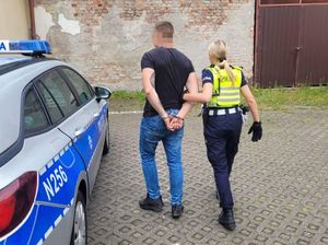 Zdjęcie przedstawiające policjantkę prowadzącą zatrzymanego mężczyznę.