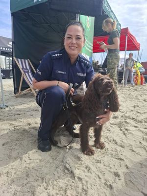 Zdjęcie przedstawiające policjantkę z psem służbowym podczas festynu na plaży miejskiej.
