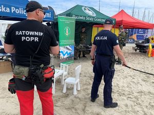 Zdjęcie przedstawiające policjanta oraz funkcjonariuszy innych służb podczas festynu na plaży miejskiej.