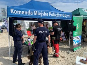 Zdjęcie przedstawiające policjantów i ratownika POPR podczas festynu na plaży miejskiej.