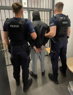 Zdjęcie przedstawiające dwóch policjantów z zatrzymanym mężczyzną.