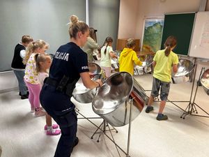 Zdjęcie przedstawiające policjantkę grającą z dziećmi na instrumentach.