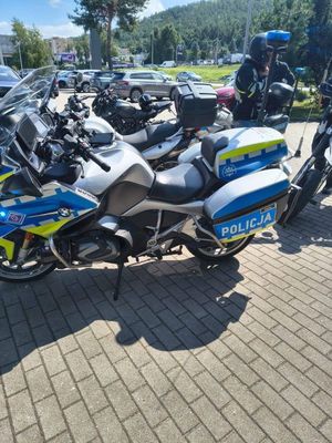 Zdjęcie przedstawiające motocykle. Na zdjęciu widać mężczyznę, a w tle pojazdu osobowe.