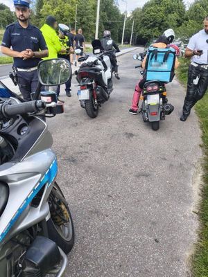 Zdjęcie przedstawiające motocykle. Na zdjęciu widać też trzech policjantów i cztery osoby, wobec których były podjęte kontrole.