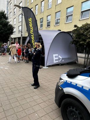 Zdjęcie przedstawiające policjantkę, w tle widać też dzieci oraz dwie dorosłe osoby.