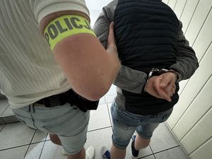 Zdjęcie poglądowe, przedstawiające policjanta prowadzącego zatrzymanego mężczyznę.