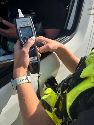 Zdjęcie przedstawiające alkomat trzymany przez policjantkę z wynikiem pomiaru.